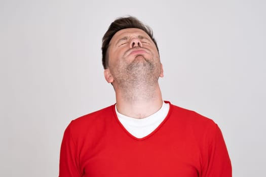 confused guy wearing red tshirt looking at camera with doubt. Studio shot. Human emotion.