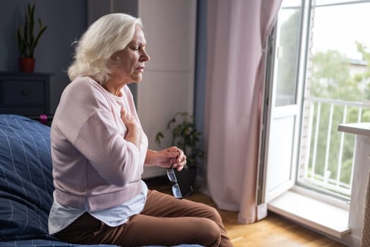 Old woman holding breast because of heart infarction . High quality photo