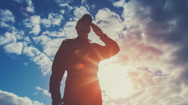 Silhouette of a proud soldier in uniform saluting against a dramatic sunset sky. Concept of military service, honor, respect, and remembrance.