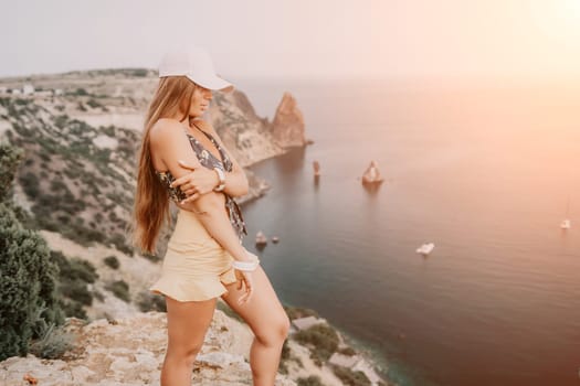 Woman travel sea. Happy tourist taking picture outdoors for memories. Woman traveler looks at the edge of the cliff on the sea bay of mountains, sharing travel adventure journey.