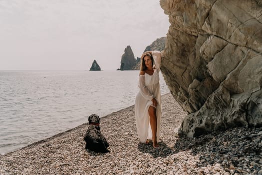 Woman travel sea. Young Happy woman in a long red dress posing on a beach near the sea on background of volcanic rocks, like in Iceland, sharing travel adventure journey