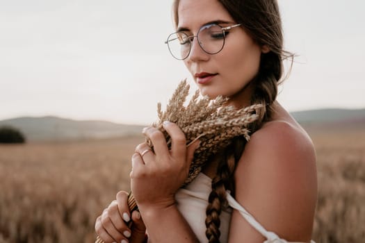 A young woman with long brown hair in braids holds wheat in a field, her eyes closed as she enjoys the moment.