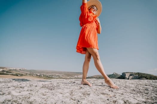 A woman in a vibrant red dress and a straw hat poses on a clifftop against a clear blue sky. The bright colors and open space evoke a sense of freedom and joy.