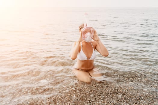 Young happy woman in white bikini put pink snorkeling mask on beach before swimming. girl having fun relaxing on beautiful beach. Beach lifestyle