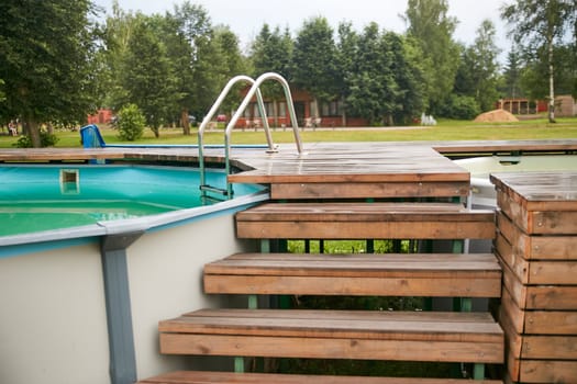 Wooden steps outdoor pool. Summer entertainment for children and adults.