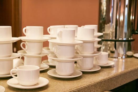 white cups and saucers on the bar counter in the cafe. coffee break. tea break. Table setting.