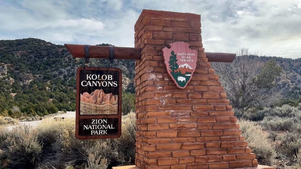 New Harmony, Utah, USA – 02.26.2024: The entrance sign for Kolob Canyons, a scenic and quiet area in Zion National Park. The surrounding landscape is arid, with red rock formations.