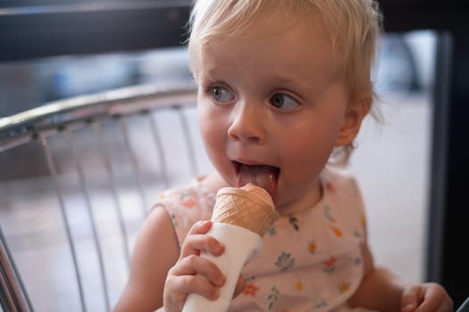 Pretty baby girl kid hold big ice cream in waffles cone with raspberry happy smiling ready to eat