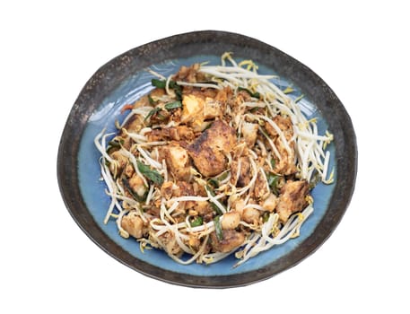 Stir-fried soft turnip cake or Fried radish cake (chai tow kway) with bean sprout and chives on ceramic plate isolated on white background with clipping path. Thai - Chinese food called Kanom Pak kad or Char Koay Kak, Top view, Selective focus.