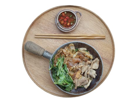 Thai stir-fried Wide Rice Noodles in Sweet Soy Sauce with Pork and Chinese kale ( Pad See-Ew ) served with chopsticks and Thai chilli fish sauce on Round woonden tray isolated on white background with clipping path. Space for text, Selective focus.