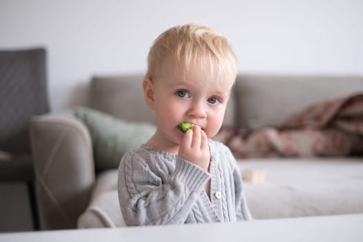 Caucasian little girl eats vegetable salad using fork.