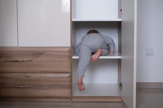 happy girl playing hide and seek in wardrobe, Active kid looking out while hiding behind the white door