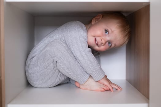 happy girl playing hide and seek in wardrobe, Active kid looking out while hiding behind the white door