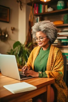 A happily retired African-American woman with gray hair works at her computer. High quality photo