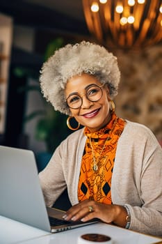 A happily retired African-American woman with gray hair works at her computer. High quality photo