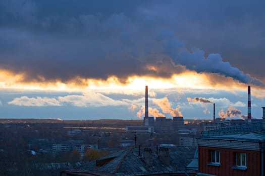 Power plant seen above residential blocks of city during sunset