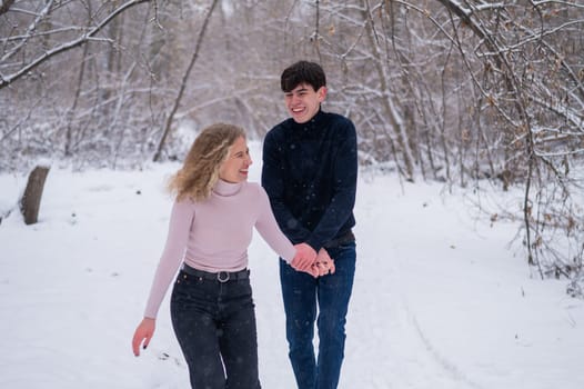 A young couple walks in the park in winter without jackets