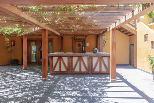 Outdoor bar area with a wooden pergola and plants, creating a relaxing and shaded space for leisure.