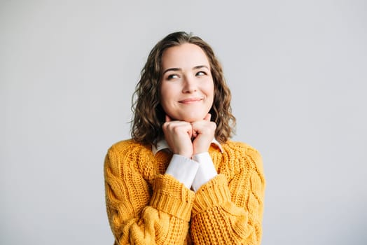 Young woman with a dreamy smile, hands resting on her chin, looking away thoughtfully. Captures a moment of contemplation and positivity. Isolated on a white background, perfect for lifestyle