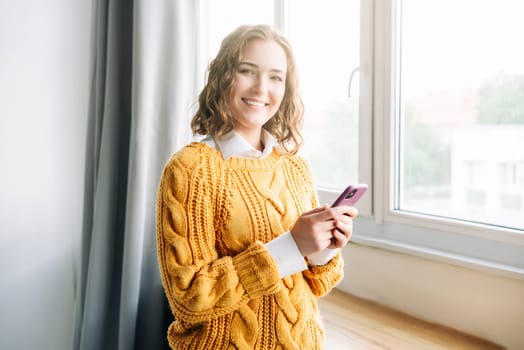 Joyful Woman Using Smartphone at Home. Smiling woman using her phone at home, enjoying online shopping and texting. Capturing a moment of happiness and modern lifestyle in a cozy indoor setting
