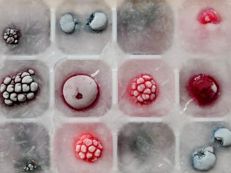 Frozen ice with berries in a container by the piece for making refreshing drinks or preserving vitamins and minerals seasonal cherries, raspberries, strawberries, blackberries, mulberries, blueberries