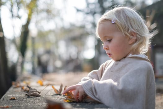 autumn outdoor portrait of beautiful happy child girl walking in park playing with leaves