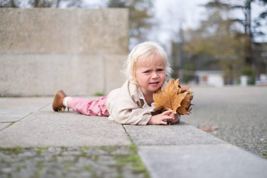 Portrait of a caucasian two years old baby girl crying outdoors. fell down