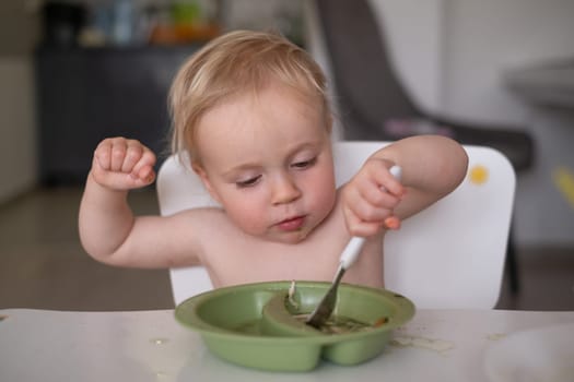 Hungry little kid eating soup with noodles with big spoon. High quality photo