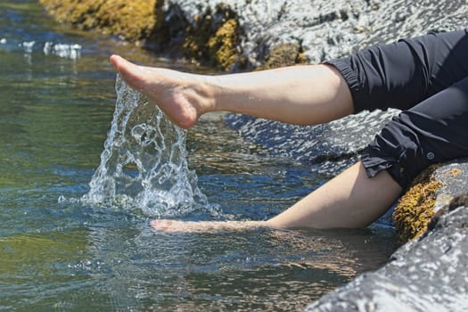 A concept lifestyle photo of the legs of a woman kicking up water from the river in north Idaho.