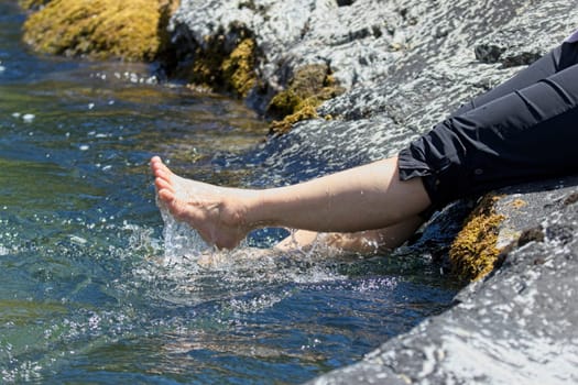 A concept lifestyle photo of the legs of a woman splashing in the water from the river in north Idaho.