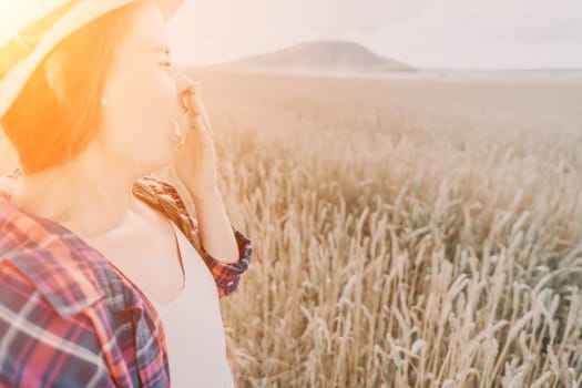 Woman farmer walks through a wheat field at sunset, touching green ears of wheat with his hands. Hand farmer is touching ears of wheat on field in sun, inspecting her harvest. Agricultural business.