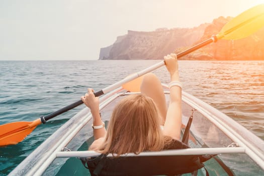 Woman in kayak back view. Happy young woman with long hair floating in transparent kayak on the crystal clear sea. Summer holiday vacation and cheerful female people having fun on the boat.