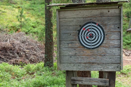 Closeup view of darts with a dart stuck into the board. Brick wall background. The dart stick is not in the center of the board