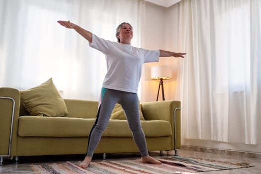 senior woman doing warmup workout at home. Fitness woman doing stretch exercise stretching her body. Elderly woman living an active lifestyle.