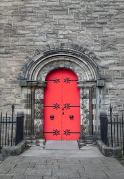 Edinburgh, Scotland - Jan 16, 2024 - Facade of arched red wooden doorway on stone wall of Mansfield Traquair Centre in Edinburgh. Scotland. Copy space, Selective focus.