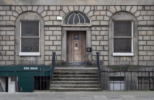 Edinburgh, Scotland - Jan 16, 2024 - Georgian architecture of House in Edinburgh. Facade of Traditional house with sash windows, wooden doorway, stone stairs and wrought iron black railings, Space for text, Selective focus.
