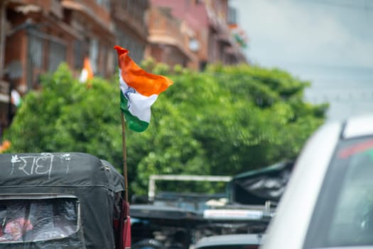 Indian tricolor flag mounted on vehicle in middle of traffic showing national pride and celebration of independence and republic day. Shot with shallow depth of field