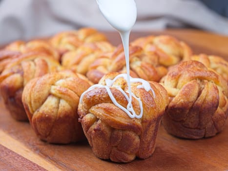 A close up of pouring glaze on homemade braided cinnamon rolls.