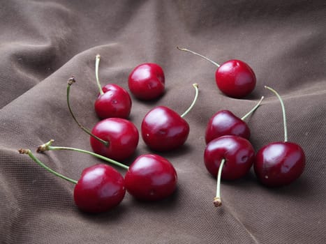 A close up photo of a bunch of cherries displayed on an old cloth.