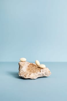 Progesterone Capsules On Stone, Blue Background. Natural Product Concept. Mockup Menopausal Hormone Therapy, Oral Route. Menopause. Cycle Changes. Vertical Copy Space. Design. High quality photo