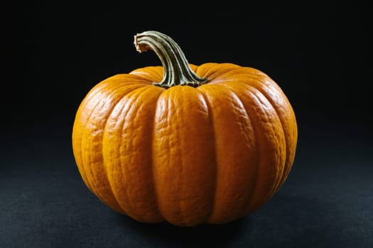 Freshly harvested orange pumpkin with a green stem, perfect for autumn or Halloween-themed designs.