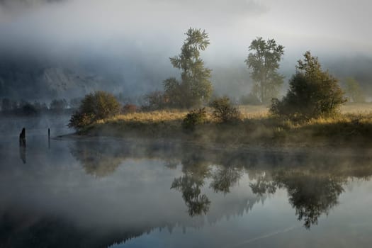 Fog  and mist layers lightly covers the calm mirror like St. Joe River near St. Maries, Idaho.