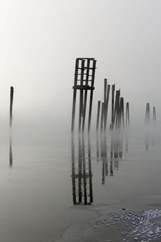 Wooden pilings rise out of the calm water on a foggy morning in January on the Pend Oreille River in north east Washington state.
