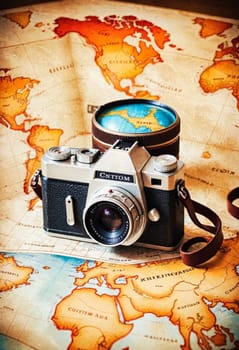 A vintage camera is set on an antique world map, evoking a sense of travel and exploration.