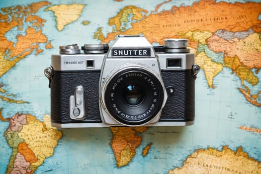 The image features a vintage camera set on a world map, blending travel and photography in a nostalgic scene.