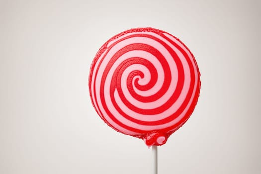 Delicious red and pink lollipop with a swirl design, ideal for satisfying a sweet tooth.
