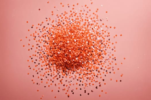 A close-up view of a surface covered in peach and silver confetti. The confetti is scattered randomly, creating a textured and sparkling background. The soft light catches the confetti, making it shimmer and shine.