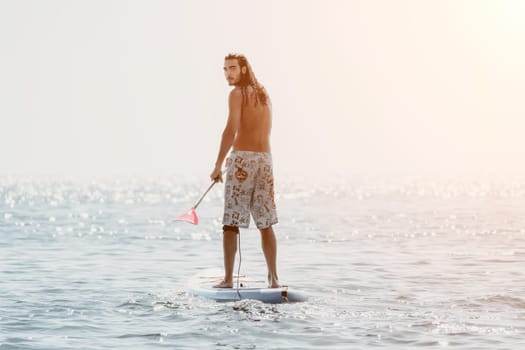 Man Sea Sup. Strong athletic man learns to paddle sup standing on board in open sea ocean on sunny day. Summer holiday vacation and travel concept. Aerial view. Slow motion.