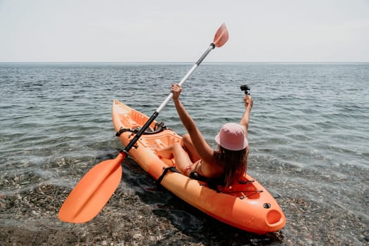 Happy smiling woman in kayak on ocean, paddling with wooden oar. Calm sea water and horizon in background