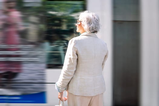 rear view of a mature woman watching the bus pass by, concept of public transport and urban lifestyle, copyspace for text